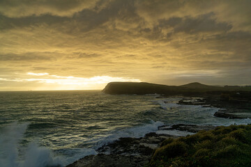 Golden clouds over stormy seas and rugged coast