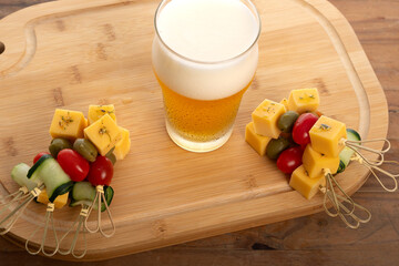 Tasty skewers and cold beer harmonizing on a wooden board