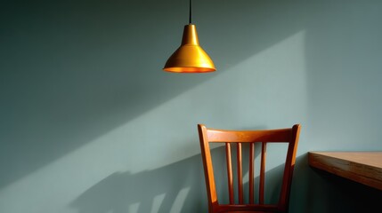 Minimalist interior featuring a wooden chair and warm pendant light against a blue wall, creating a cozy and inviting atmosphere for relaxation or contemplation.