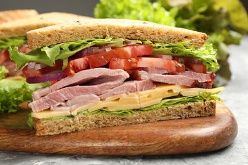 Delicious sandwich with ham, cheese and vegetables on grey textured table, closeup