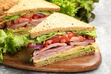 Delicious sandwiches with ham, cheese and vegetables on grey textured table, closeup