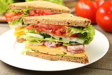 Tasty sandwiches with ham, cheese and vegetables on wooden table, closeup