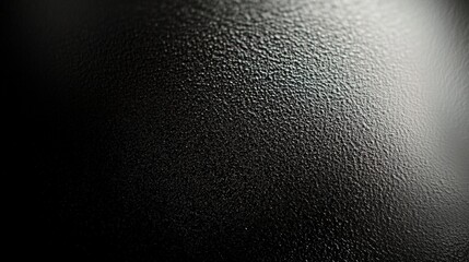 A close-up of a textured black surface, showcasing a play of light and shadow, emphasizing its rich, tactile quality.