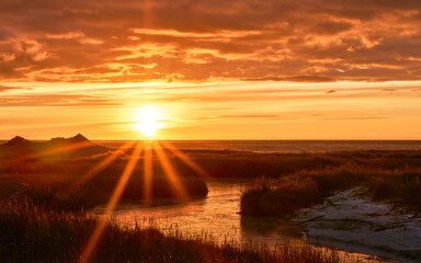 Golden sunbeams pierce the dramatic orange sky