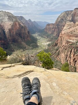 Hiker sitting on rocks at the top of Angels Landing hike overlooking the valley of Zion National Park, Springdale, Utah, USA