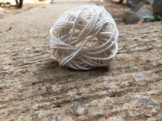 A white yarn ball placed on a rough concrete surface under natural light, showing fine texture, soft tones, and aesthetic composition in close-up view.