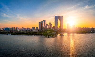 Fototapeta premium Aerial view of the modern downtown cityscape with skyscrapers and a large lake during a beautiful golden sunset in Suzhou.
