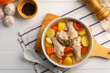 Chicken Potato Soup,Potatoes Soup With Chicken wing(drumettes) carrot tomato and onion in white bowl.Clear soup.Top view.