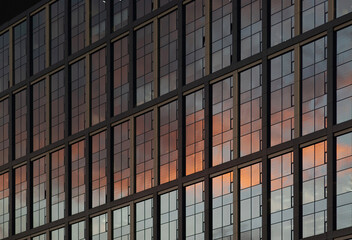 Modern office building with sunset reflected in glass windows.