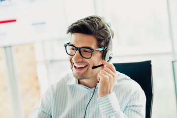 Smiling businessman wearing a headset while working in an office environment, representing communication and professionalism