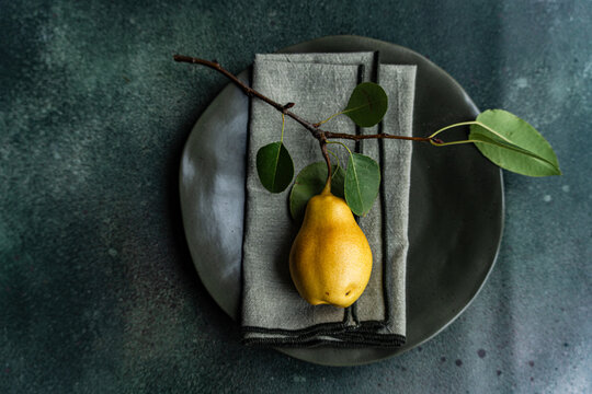 Overhead view of a rustic autumnal place setting on a table with a ripe pear