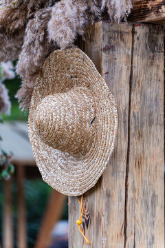 Close-up of an Old straw hat hanging on a wooden wall outside a house