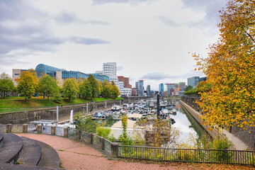Obraz premium Gehry Designed Twisted Buildings Overlooking Busy Marina with Docked Boats and Autumn Trees in Düsseldorf Germany