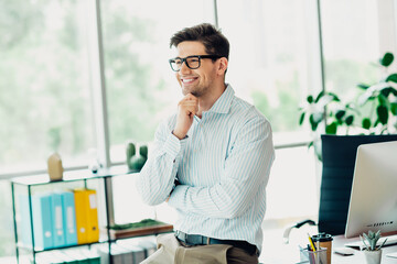 Confident young businessman smiling in a stylish modern office environment, expressing success, positivity, and professionalism