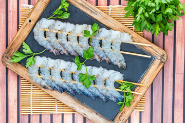 Uncooked black tiger prawns skewers - overhead view