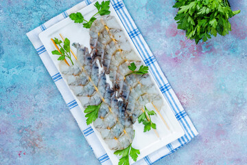 Uncooked black tiger prawns skewers - overhead view