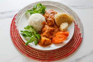 Mafé à la viande – plat traditionnel africain à la sauce arachide, présenté sur un dessous de plat africain tissé. 