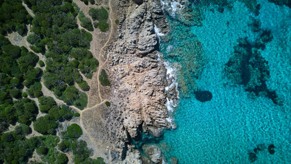 Beautiful drone shot of the Sardinian seaside, blue of the sea, green of the forest and the rocky beach in between © Zsuzsanna