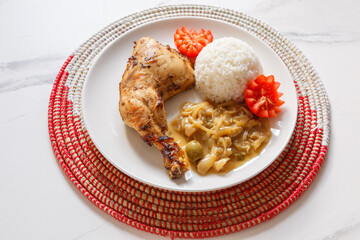 Poulet Yassa – plat traditionnel sénégalais aux oignons et citron, présenté sur un dessous de plat africain tissé. Plat emblématique du Sénégal et de la cuisine d’Afrique de l’Ouest.