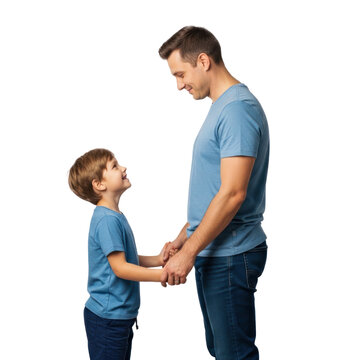 A man and a boy holding hands, smiling, and looking at each other.