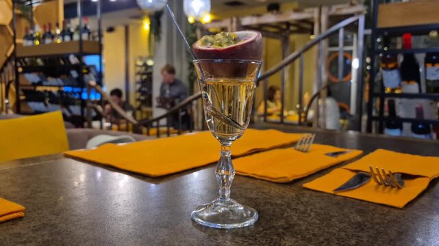 A glass with an alcoholic drink decorated with fresh passion fruit, close-up