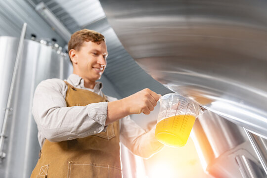 Caucasian male worker brewing beer in modern brewery setting, Quality control