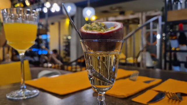 A glass with an alcoholic drink decorated with fresh passion fruit, close-up
