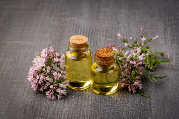 Essential oil in bottle with blooming valerian plant