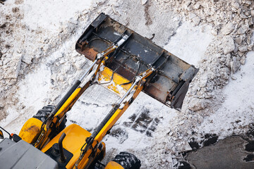 Aerial view Yellow tractor clearing snow on icy road in winter landscape