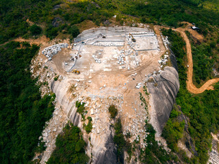 Aerial view of stone and marble quarry in lush green landscape with excavation machinery