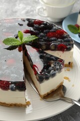 Taking piece of delicious cheesecake with berries at grey table, closeup