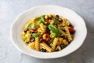 Close-up of fresh homemade colorful vegan fusilli pasta salad on the plate on the table.