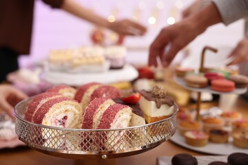 Different delicious desserts and people at buffet table, selective focus