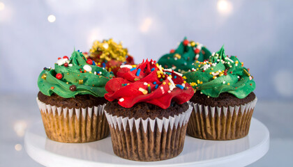 Festively Decorated Cupcakes with Vibrant Green and Red Frosting on White Pedestal with Blurred Background