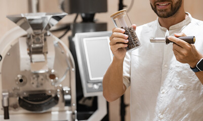 Young caucasian male roasting coffee beans in modern industrial setting
