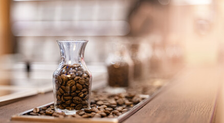 Fresh coffee beans after roasting in glass bottle for variety selection blurred background, banner factory roastery
