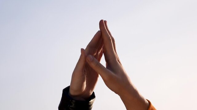 High five between two hands reaching into soft sky light showing connection partnership teamwork friendship gesture and celebration as fingers touch indicating trust collaboration and shared win