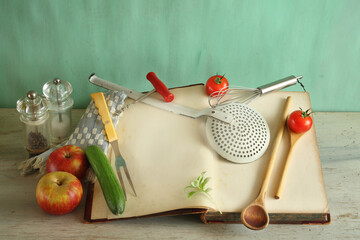 Blank vintage recipe cookbook and old kitchen utensils and vegetables, free copy space for recipes.