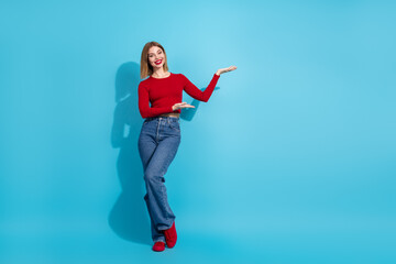 Charming young woman in a stylish casual outfit presenting on a vibrant blue background with a lovely smile