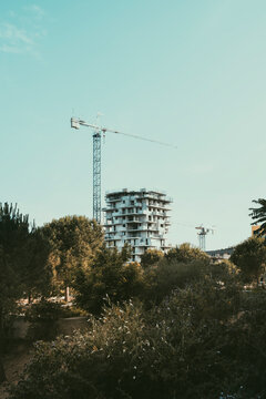 Crane and modern building structure surrounded by trees and vegetation in Montpellier, France, symbolizing urban growth and architectural development in progress