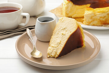 Delicious Basque cheesecake, chocolate sauce and tea on white wooden table, closeup