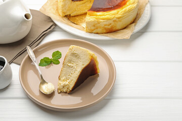 Delicious Basque cheesecake with mint, chocolate sauce and tea on white wooden table, closeup. Space for text