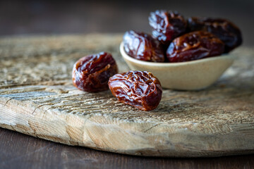 A close up view of medjool dates with a bowl of them in soft focus in behind.
