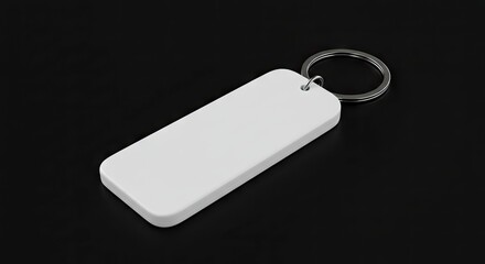 A white rectangular keychain with a silver ring lies on a black surface