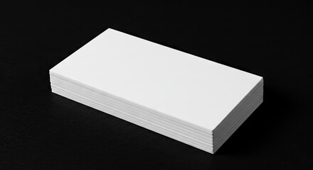 A neat stack of blank white rectangular cards rests on a plain black surface