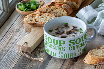 A cup of homemade cream of mushroom soup served with bread, ready for eating.