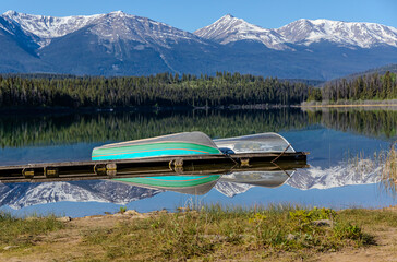 A scenic mountain view reflecting into a lake with two boats on a dock.