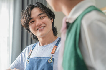 Asian mature man enjoys morning coffee at cafe using drip coffee bag in beige cup on white wood...
