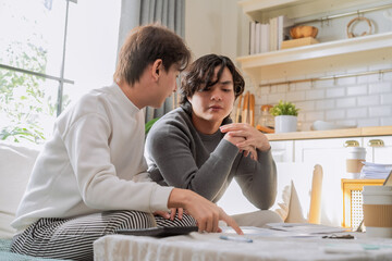 Asian LGBTQ male couple reviews monthly financial bills and household expenses together at home, managing shared budget planning, savings goals and responsible money management for their future 