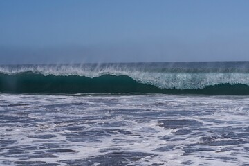 Strong waves breaking on the Atlantic shore near El Medano, Tenerife. Natural power and texture of sea water under clear blue sky — symbol of energy and motion.